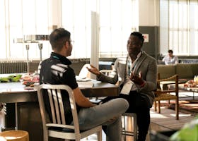 Two men having a casual discussion in a bright indoor setting, highlighting mentorship.