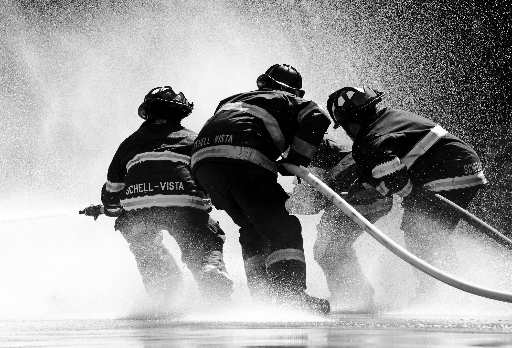 Firefighters in full gear battle heavy water spray in an intense operation.