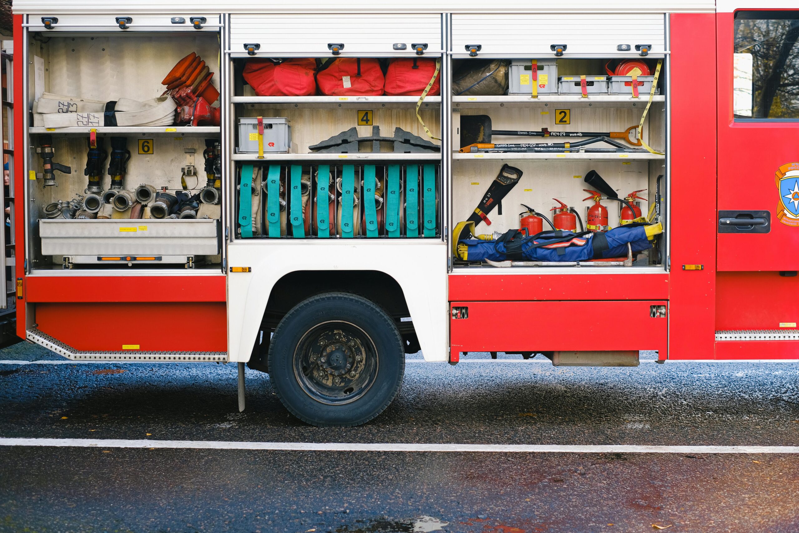 Close-up view of a fire truck's open compartments revealing essential firefighting equipment.